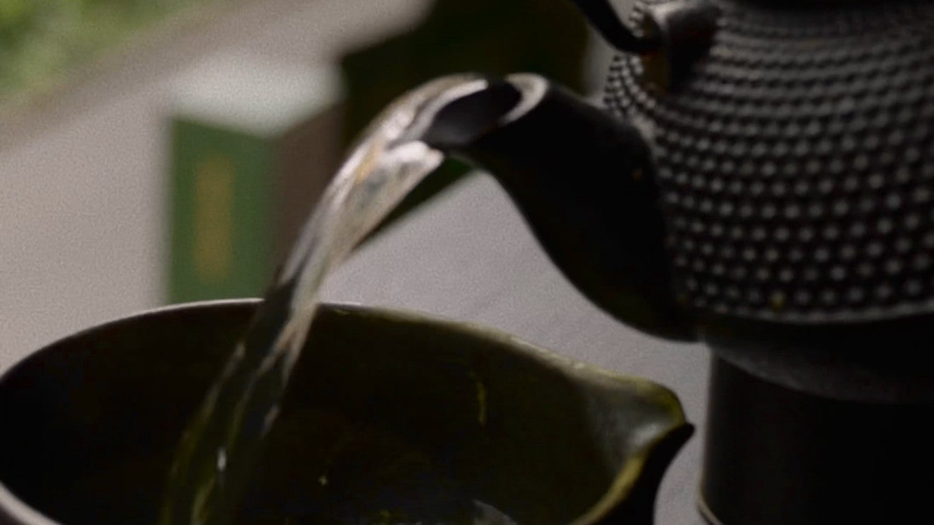 Hot water poured from a cast-iron teapot into a matcha bowl