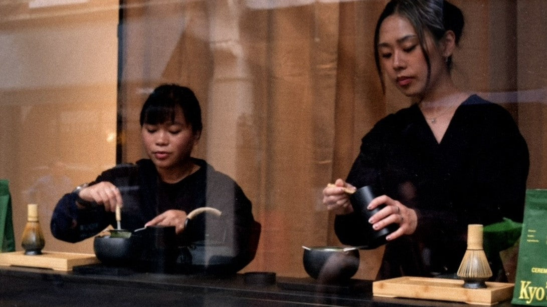 Two baristas whisking Kyo's ceremonial matcha in a shop window